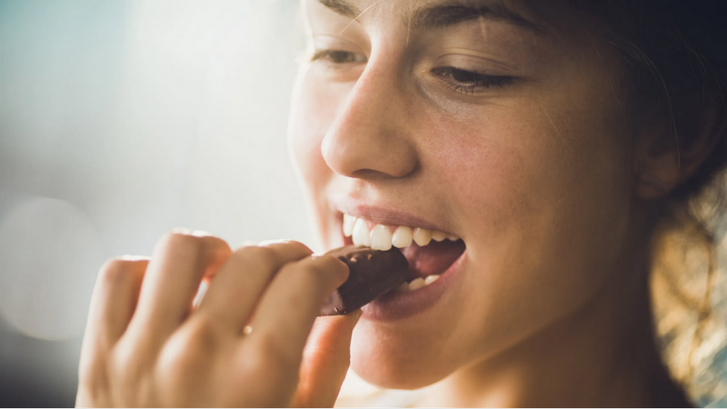 Can eating chocolate cause acne? A teenage girl with pimples holding a chocolate bar