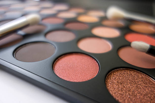 A close-up of a diverse eyeshadow palette with brushes, showcasing vibrant colors for year-round beauty.